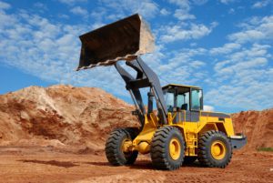 wheel loader bulldozer with fully raised bucket over blue cloudy sky standing in sandpit